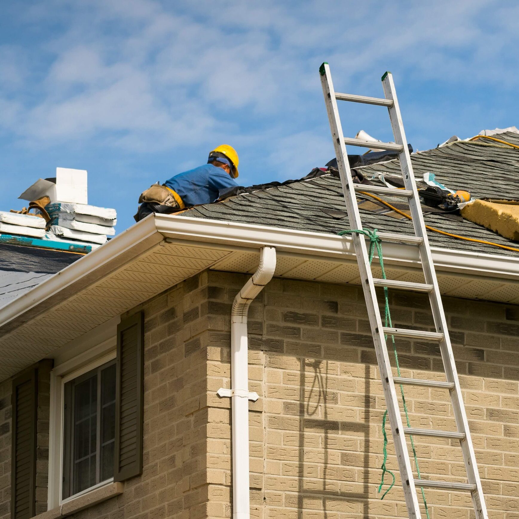 Roof worker installing new shingles on a roof of a house